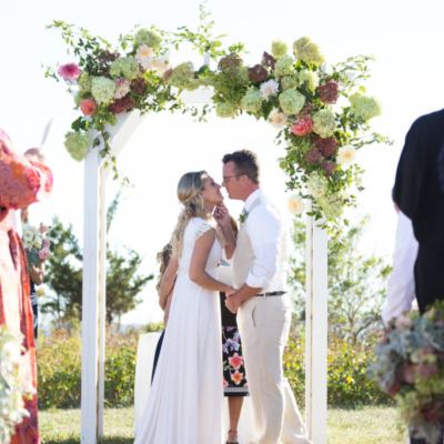 bride and groom under arbor of flowers